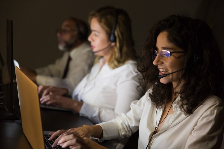 Equipe de profissionais oferecendo sustentação técnica para e-commerce, trabalhando em computadores com fones de ouvido, em um ambiente de suporte técnico.