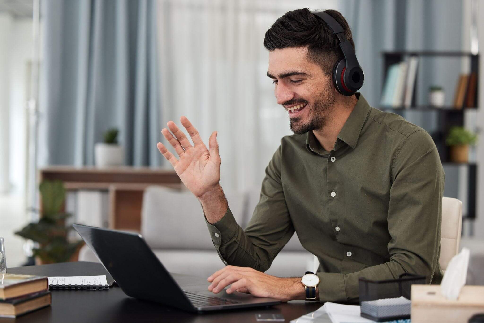 Profissional sorridente usa fone de ouvido em uma sales call pelo notebook, transformando diálogos consultivos em receita previsível para a empresa durante o trabalho home office.