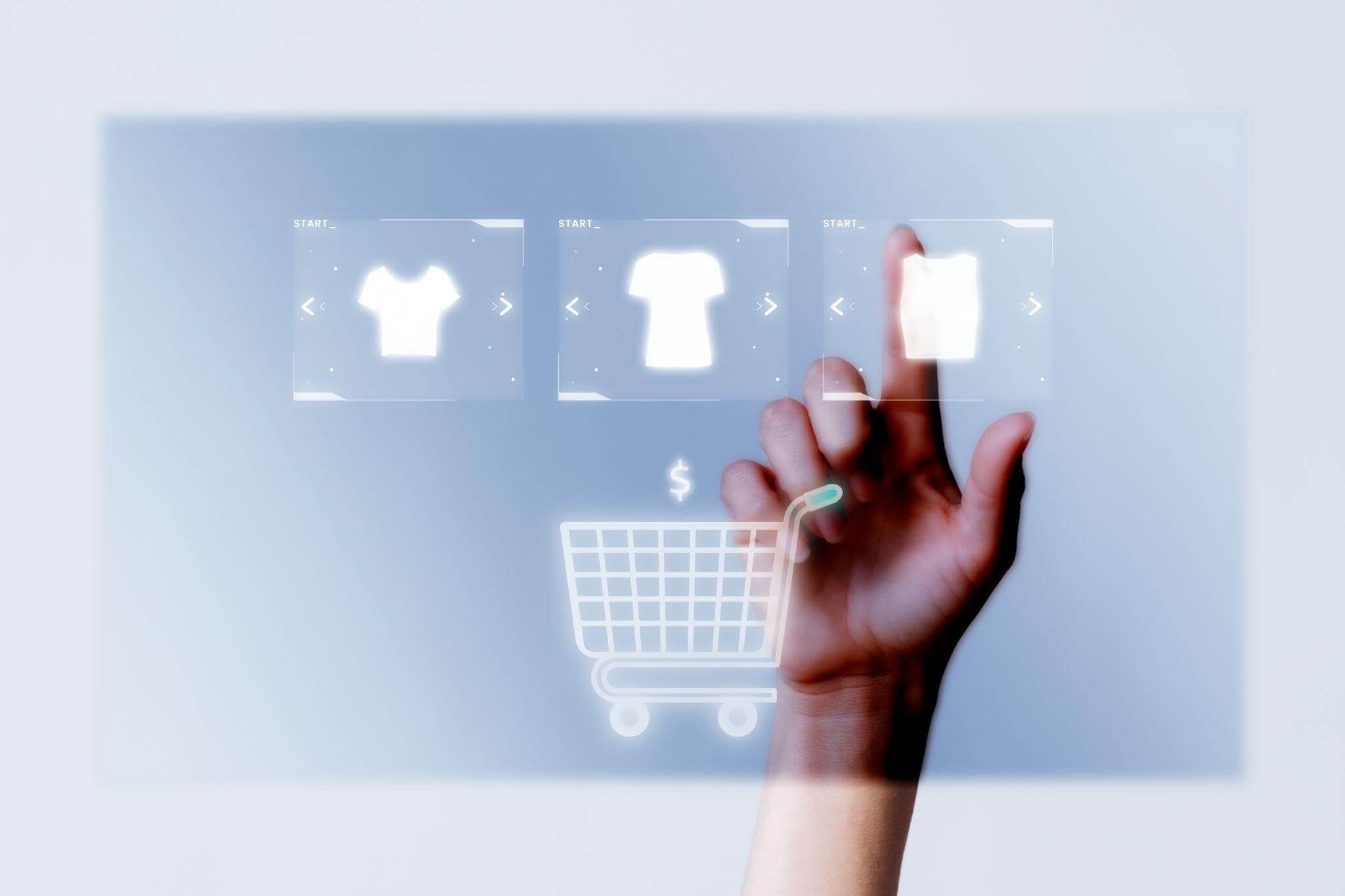 Uma mão estendida interage com uma tela digital translúcida flutuante, selecionando opções de camisetas em uma interface moderna de e-commerce cognitivo integrada à IA generativa. Abaixo das opções de produtos, há o ícone luminoso de um carrinho de compras com um cifrão acima dele, contra um fundo clean e minimalista.